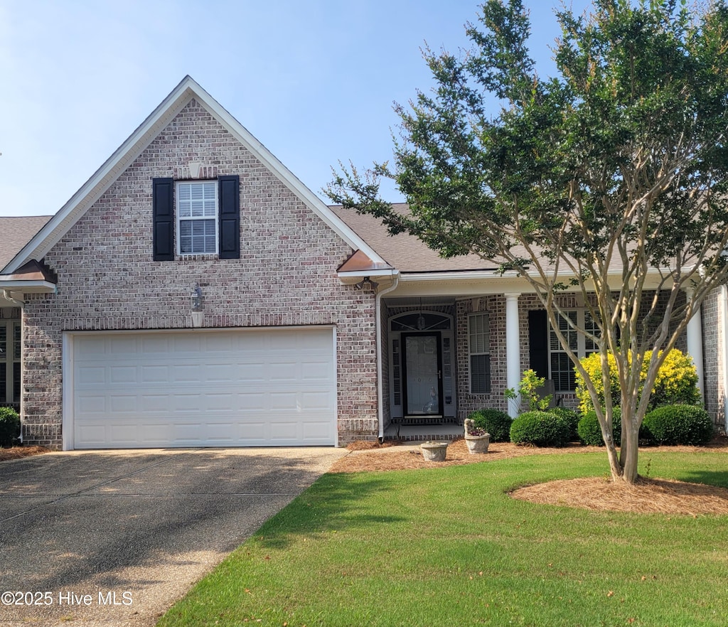 1014 N Sanderling Dr, Leland, NC 28451 - view of front of home with brick siding, driveway, a front lawn, covered porch, and roof with shingles