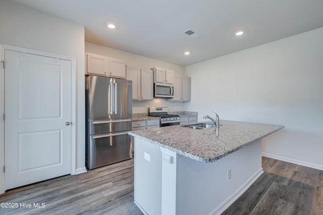 5380 Black Oak Ct, Winnabow, NC 28479 - kitchen with appliances with stainless steel finishes, wood finished floors, a kitchen island with sink, light stone countertops, and gray cabinets