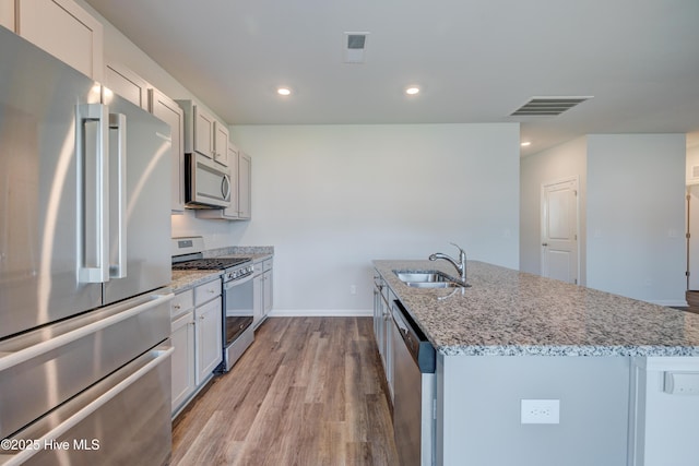 5380 Black Oak Ct, Winnabow, NC 28479 - kitchen featuring stainless steel appliances, light wood finished floors, an island with sink, light stone countertops, and recessed lighting
