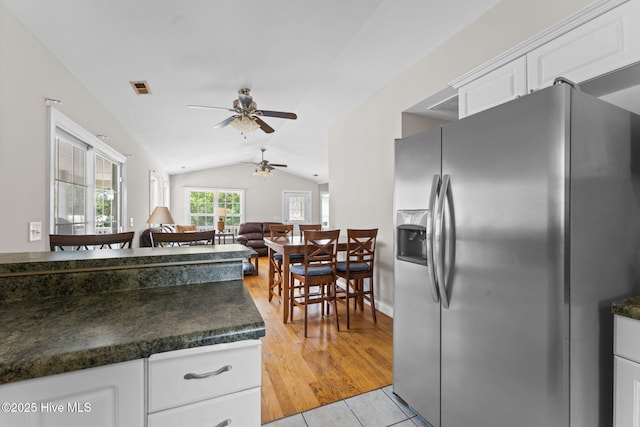 126 NE 5th St, Oak Island, NC 28465 - kitchen featuring stainless steel refrigerator with ice dispenser, dark countertops, ceiling fan, lofted ceiling, and white cabinetry