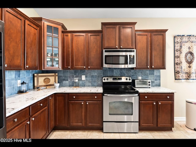 1232 Fence Post Ln, Carolina Shores, NC 28467 - kitchen featuring stainless steel appliances, backsplash, glass insert cabinets, and light stone counters