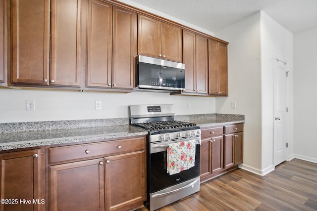 122 Mill Run Loop, South Mills, NC 27976 - kitchen featuring stainless steel appliances, dark wood-style floors, baseboards, light stone countertops, and brown cabinets