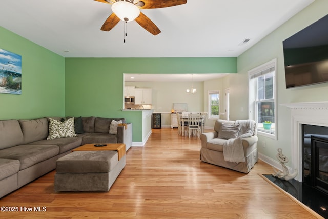 6005 Otter Tail Trl, Wilmington, NC 28412 - living area with a glass covered fireplace, light wood finished floors, ceiling fan, and a chandelier