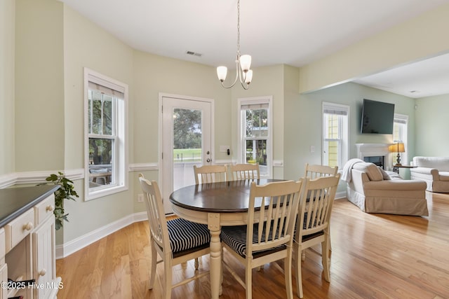 6005 Otter Tail Trl, Wilmington, NC 28412 - dining area with light wood-style floors, a chandelier, and a fireplace