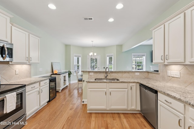 6005 Otter Tail Trl, Wilmington, NC 28412 - kitchen featuring appliances with stainless steel finishes, a peninsula, recessed lighting, tasteful backsplash, and light wood finished floors