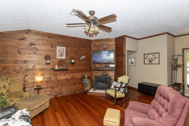 108 Western Trl, Carthage, NC 28327 - living room featuring a wood stove, a ceiling fan, wood finished floors, ornamental molding, and wood walls