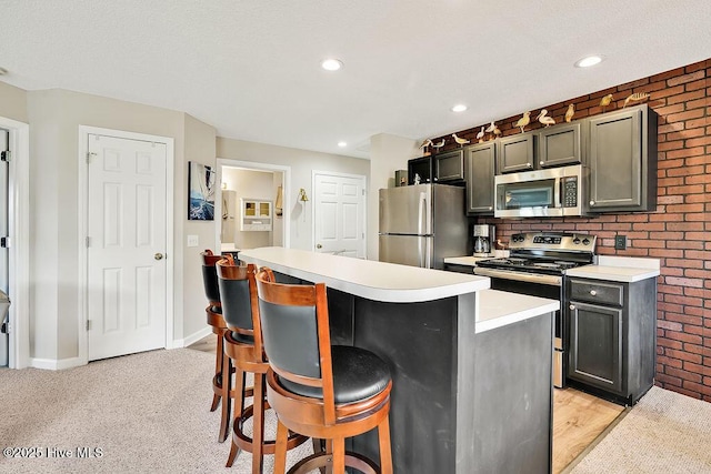 3350 Club Villas Dr # 105, Southport, NC 28461 - kitchen with appliances with stainless steel finishes, light countertops, a kitchen bar, a kitchen island, and recessed lighting
