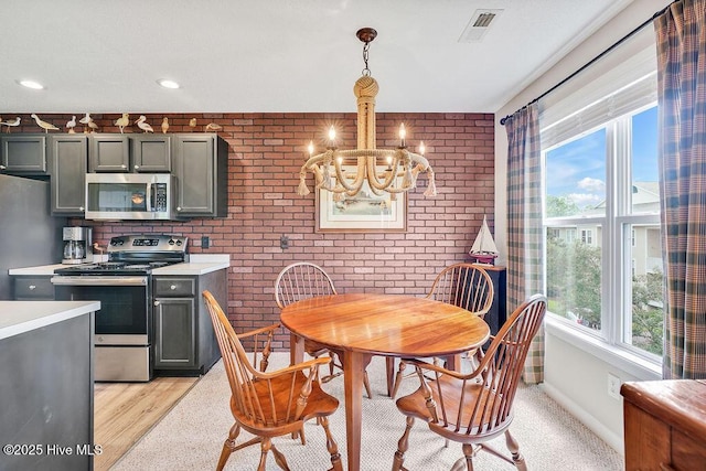 3350 Club Villas Dr # 105, Southport, NC 28461 - kitchen featuring appliances with stainless steel finishes, a chandelier, light countertops, brick wall, and hanging light fixtures