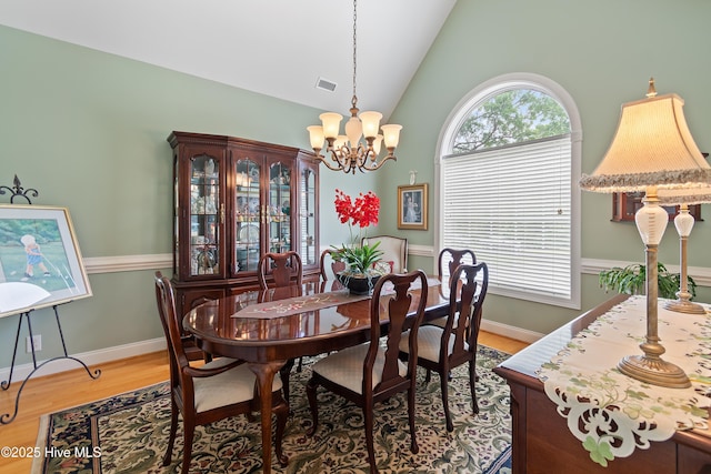 3254 Beaver Creek Dr SE, Southport, NC 28461 - dining space featuring a chandelier, light wood finished floors, high vaulted ceiling, and baseboards