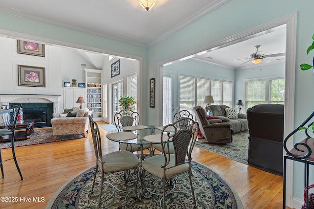 3254 Beaver Creek Dr SE, Southport, NC 28461 - dining room featuring a fireplace, light wood finished floors, ceiling fan, ornamental molding, and lofted ceiling