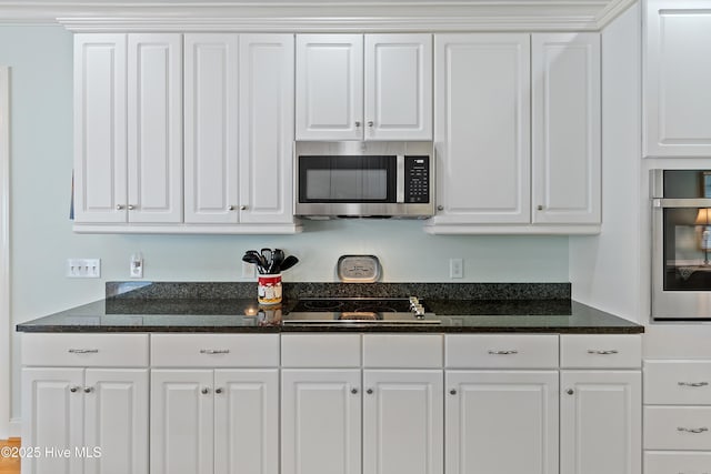 3254 Beaver Creek Dr SE, Southport, NC 28461 - kitchen with stainless steel appliances, white cabinets, and dark stone countertops