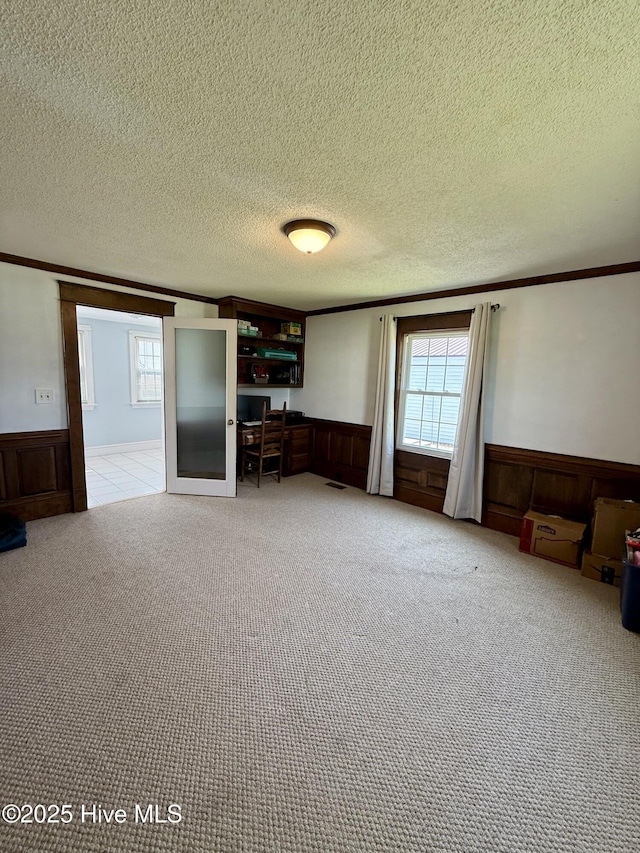 5934 NC-42, Macclesfield, NC 27852 - unfurnished living room with ornamental molding, a wainscoted wall, a textured ceiling, and light carpet