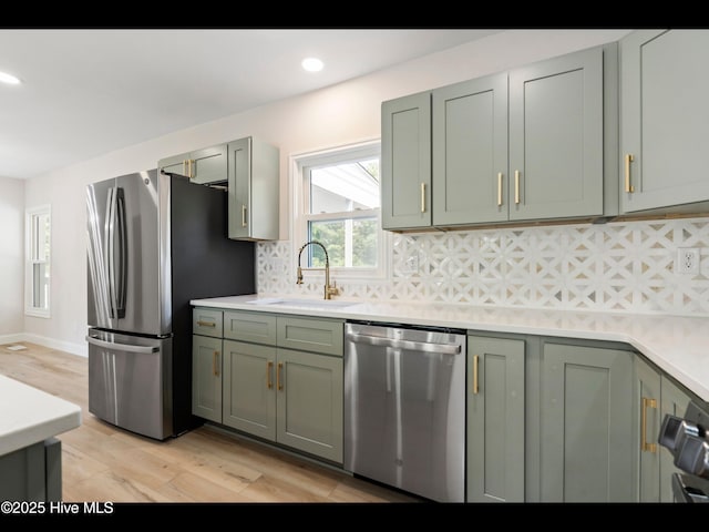109 Inlet Ct, Hampstead, NC 28443 - kitchen with appliances with stainless steel finishes, a sink, light wood-type flooring, backsplash, and light countertops