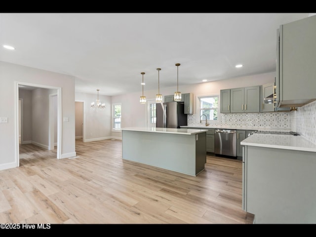 109 Inlet Ct, Hampstead, NC 28443 - kitchen featuring appliances with stainless steel finishes, a chandelier, light wood-type flooring, decorative backsplash, and a kitchen island