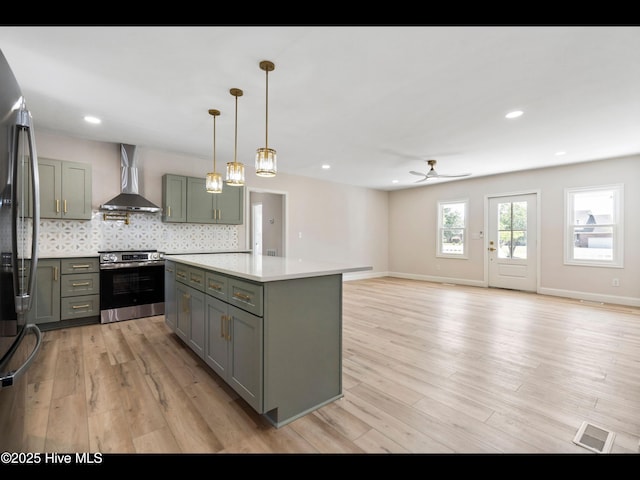 109 Inlet Ct, Hampstead, NC 28443 - kitchen with stainless steel appliances, wall chimney exhaust hood, gray cabinets, ceiling fan, and light wood finished floors