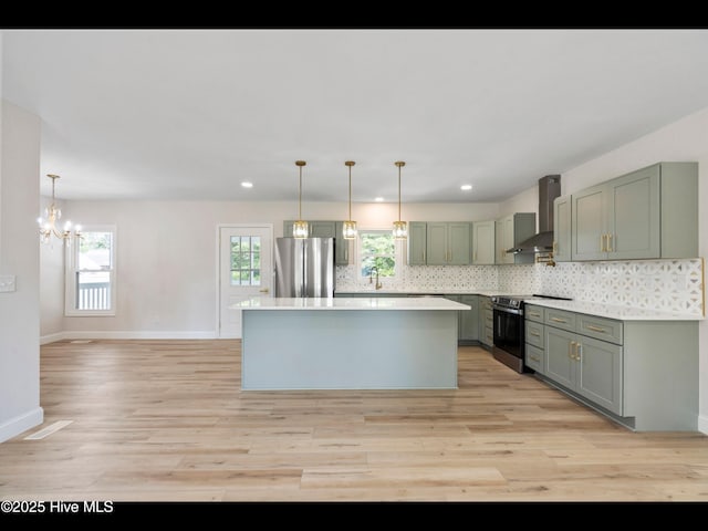 109 Inlet Ct, Hampstead, NC 28443 - kitchen with appliances with stainless steel finishes, wall chimney exhaust hood, light wood finished floors, light countertops, and a center island