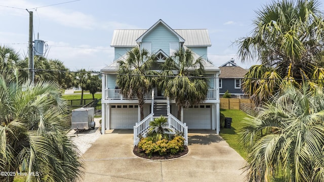 209 Georgia Ave, Carolina Beach, NC 28428 - coastal home featuring stairs, a garage, covered porch, concrete driveway, and metal roof
