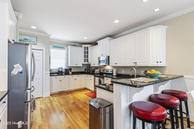 209 Georgia Ave, Carolina Beach, NC 28428 - kitchen featuring stainless steel appliances, a peninsula, light wood-style flooring, a breakfast bar, and white cabinetry