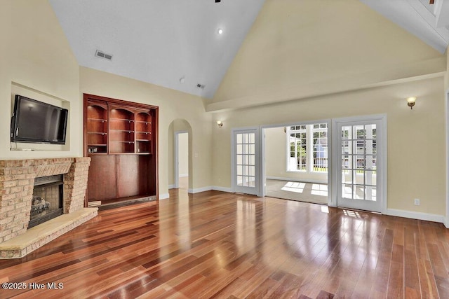 205 S Grist Mill Rd, Hampstead, NC 28443 - unfurnished living room with high vaulted ceiling, a fireplace, baseboards, arched walkways, and wood finished floors