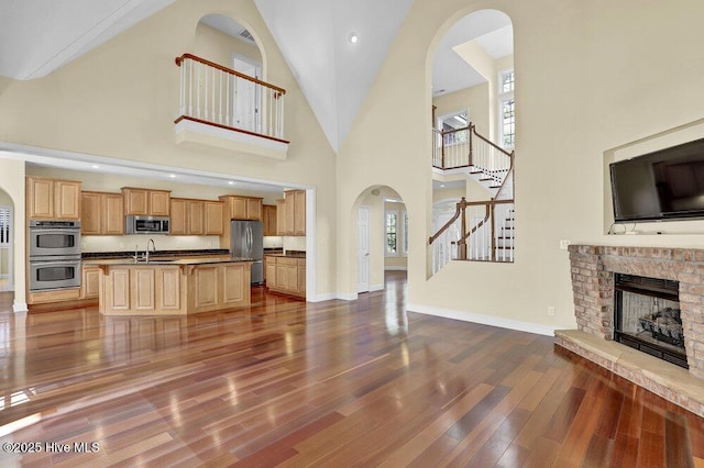 205 S Grist Mill Rd, Hampstead, NC 28443 - unfurnished living room with a sink, dark wood-style floors, stairway, high vaulted ceiling, and a fireplace with raised hearth