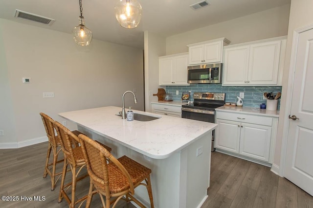 873 Bourne Dr SW, Ocean Isle Beach, NC 28469 - kitchen with appliances with stainless steel finishes, a sink, dark wood-style floors, decorative backsplash, and an island with sink
