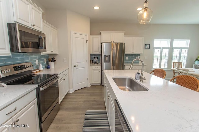 873 Bourne Dr SW, Ocean Isle Beach, NC 28469 - kitchen featuring appliances with stainless steel finishes, a sink, white cabinetry, backsplash, and light stone counters