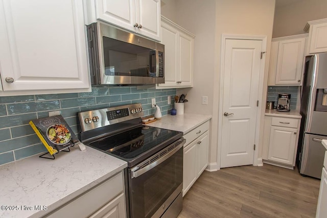 873 Bourne Dr SW, Ocean Isle Beach, NC 28469 - kitchen with stainless steel appliances, light wood-type flooring, white cabinets, tasteful backsplash, and light stone countertops
