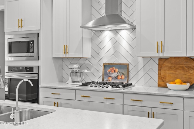 386 Yucca Ln, Wilmington, NC 28412 - kitchen with wall chimney exhaust hood, appliances with stainless steel finishes, a sink, tasteful backsplash, and white cabinetry