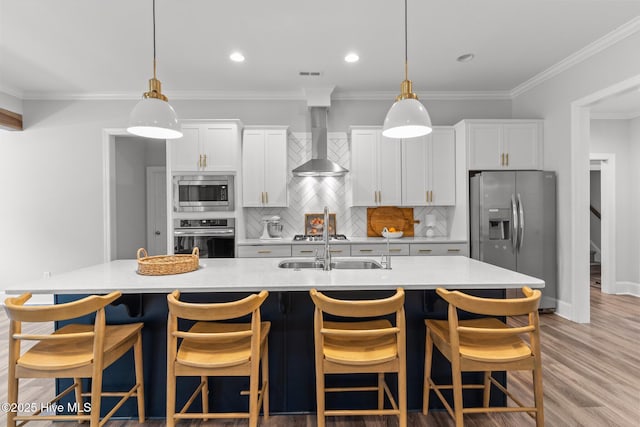 386 Yucca Ln, Wilmington, NC 28412 - kitchen featuring appliances with stainless steel finishes, wall chimney range hood, an island with sink, light countertops, and crown molding