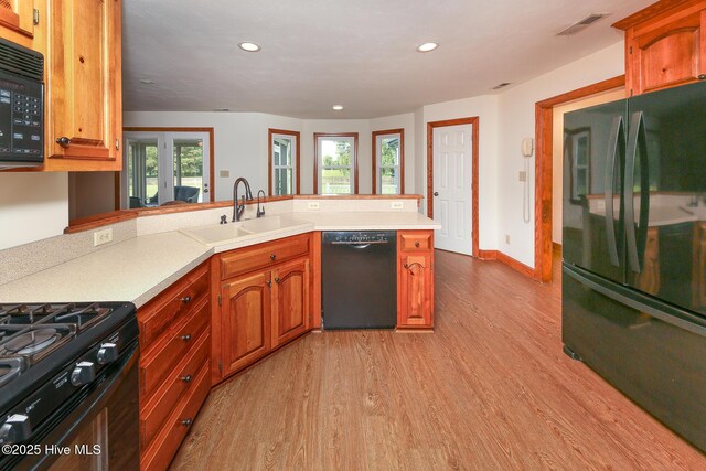 813 Puddin Ridge Rd, Moyock, NC 27958 - kitchen with black appliances, a sink, light wood-type flooring, a peninsula, and light countertops