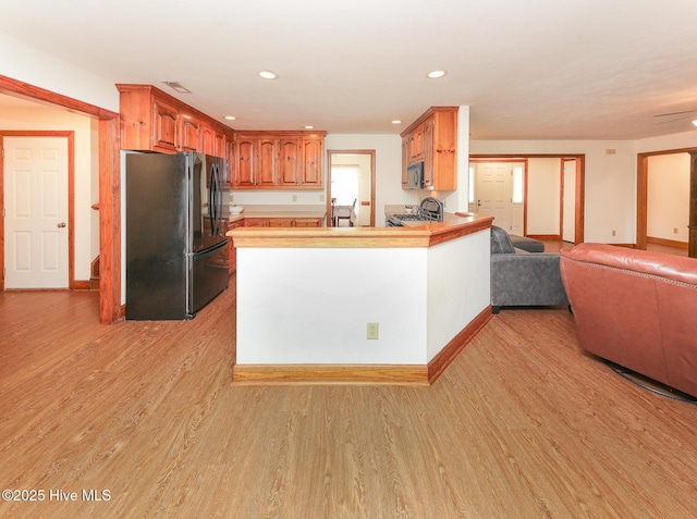 813 Puddin Ridge Rd, Moyock, NC 27958 - kitchen with black appliances, open floor plan, light wood-style floors, a peninsula, and light countertops