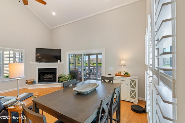 632 Settlers Ln, Kure Beach, NC 28449 - dining area featuring high vaulted ceiling, a fireplace with raised hearth, light wood-style flooring, ceiling fan, and healthy amount of natural light