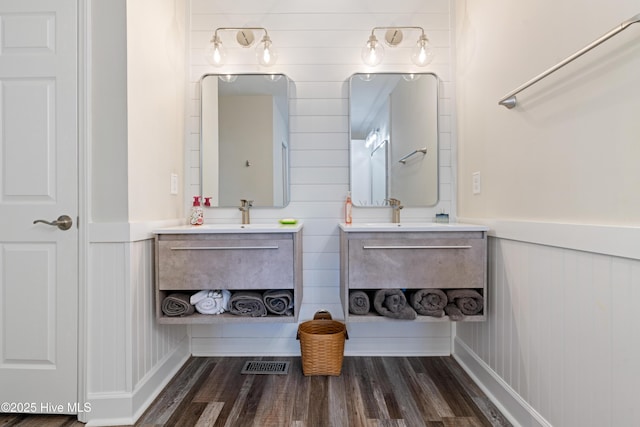 632 Settlers Ln, Kure Beach, NC 28449 - full bathroom with two vanities, wood finished floors, a decorative wall, and a wainscoted wall