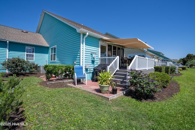 632 Settlers Ln, Kure Beach, NC 28449 - back of house featuring a lawn, a wooden deck, roof with shingles, and a patio area