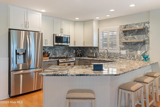 632 Settlers Ln, Kure Beach, NC 28449 - kitchen featuring stainless steel appliances, light stone countertops, a peninsula, a breakfast bar, and recessed lighting