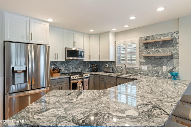 632 Settlers Ln, Kure Beach, NC 28449 - kitchen with appliances with stainless steel finishes, light stone counters, a peninsula, open shelves, and recessed lighting