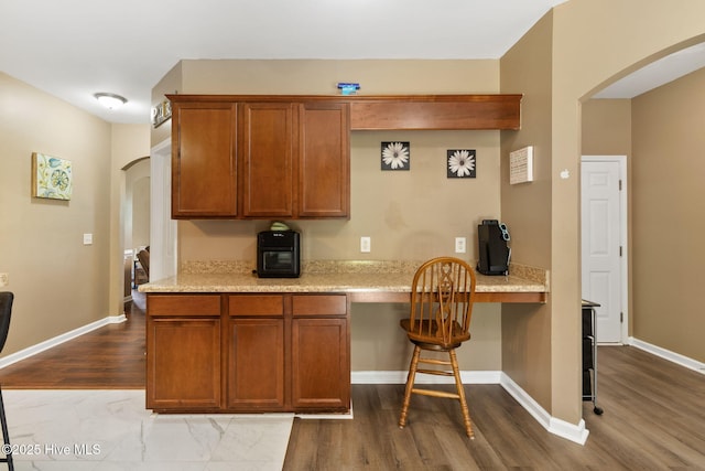 40 Sedgefield Ln, Spring Lake, NC 28390 - kitchen with arched walkways, dark wood finished floors, brown cabinetry, a kitchen bar, and baseboards