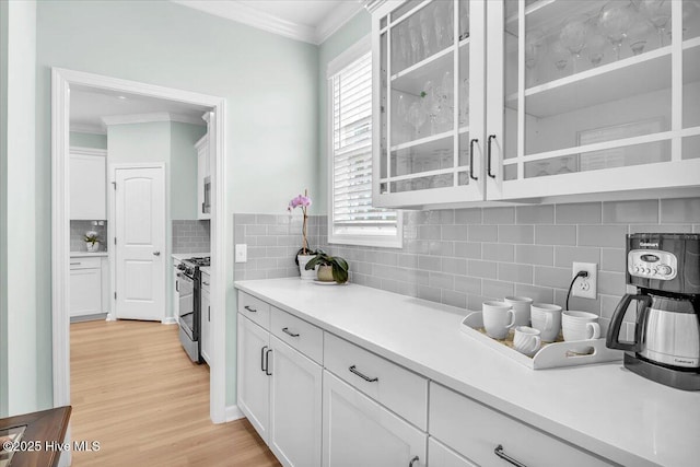 1233 Lt Congleton Rd, Wilmington, NC 28409 - kitchen with crown molding, range with gas stovetop, white cabinetry, tasteful backsplash, and light wood-style flooring
