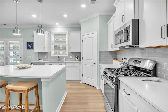 1233 Lt Congleton Rd, Wilmington, NC 28409 - kitchen featuring appliances with stainless steel finishes, a kitchen bar, crown molding, light wood-style floors, and white cabinets