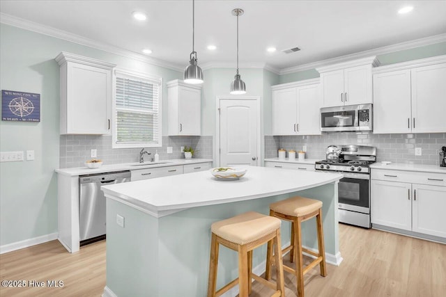 1233 Lt Congleton Rd, Wilmington, NC 28409 - kitchen featuring appliances with stainless steel finishes, a kitchen island, light wood finished floors, backsplash, and white cabinetry