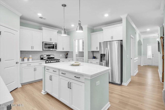1233 Lt Congleton Rd, Wilmington, NC 28409 - kitchen with appliances with stainless steel finishes, white cabinets, light wood-style floors, tasteful backsplash, and ornamental molding