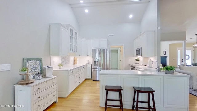 2019 Royal Pines Dr, New Bern, NC 28560 - kitchen with appliances with stainless steel finishes, a sink, a peninsula, glass insert cabinets, and high vaulted ceiling