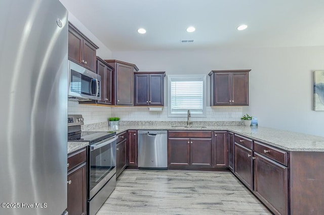 1000 Spot Cir, New Bern, NC 28562 - kitchen featuring stainless steel appliances, a sink, a peninsula, light stone countertops, and decorative backsplash
