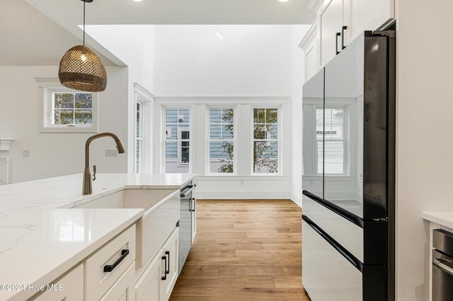 1605 E Oak Island Dr, Oak Island, NC 28465 - kitchen with freestanding refrigerator, decorative light fixtures, light wood-style flooring, and white cabinetry