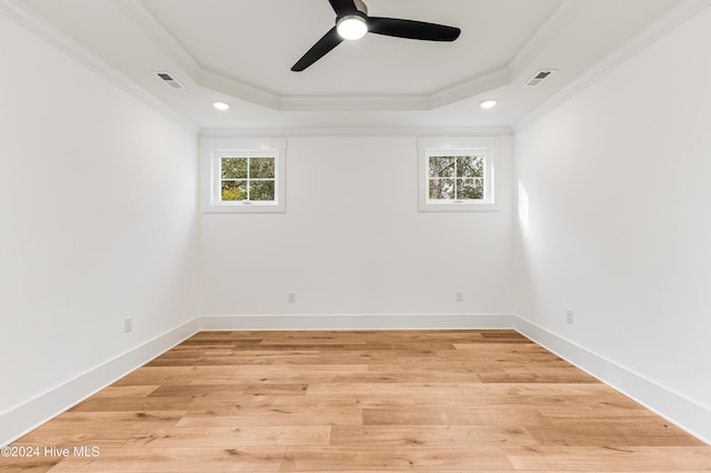 1605 E Oak Island Dr, Oak Island, NC 28465 - empty room featuring a tray ceiling, plenty of natural light, ornamental molding, ceiling fan, and light wood-style flooring