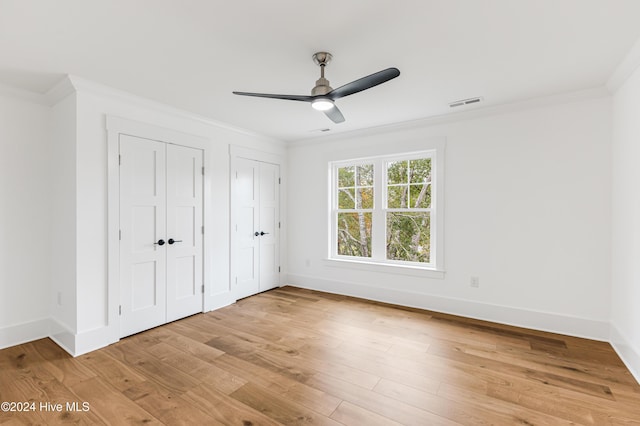 1605 E Oak Island Dr, Oak Island, NC 28465 - unfurnished bedroom with ornamental molding, multiple closets, light wood-style floors, and baseboards