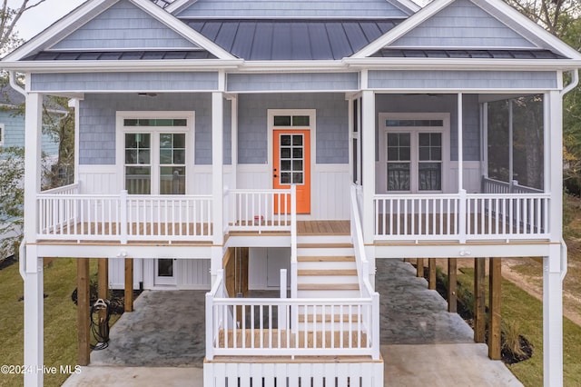 1605 E Oak Island Dr, Oak Island, NC 28465 - coastal inspired home featuring a carport, concrete driveway, a standing seam roof, and covered porch