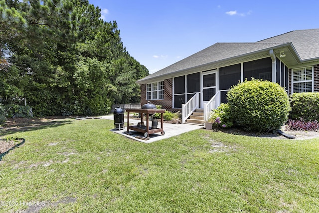 3863 Daphine Ct, Wilmington, NC 28409 - rear view of property featuring a shingled roof, a sunroom, a patio area, a lawn, and brick siding