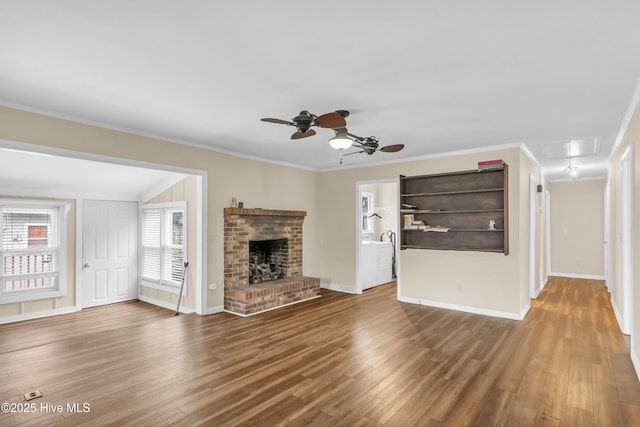 214 Frink Dr, Southport, NC 28461 - unfurnished living room with attic access, a ceiling fan, wood finished floors, crown molding, and a brick fireplace