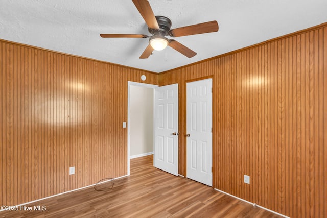 214 Frink Dr, Southport, NC 28461 - unfurnished bedroom with wood finished floors, wooden walls, a ceiling fan, and crown molding
